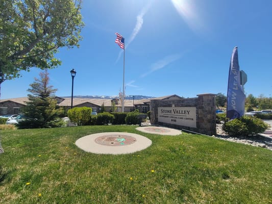 Sign of Stone Valley Memory Care Center with flag in the background