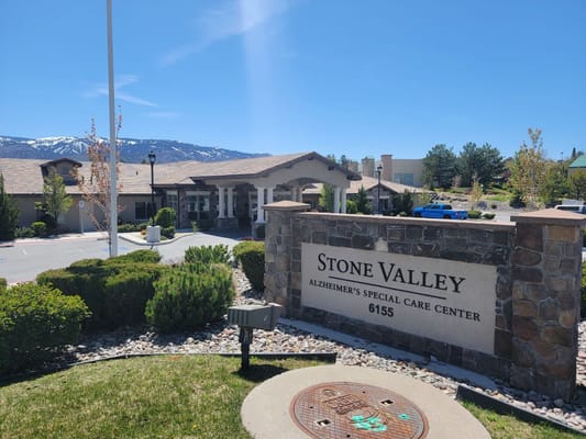 Stone Valley Memory Care entrance sign and facility with snow-capped mountains in the background.