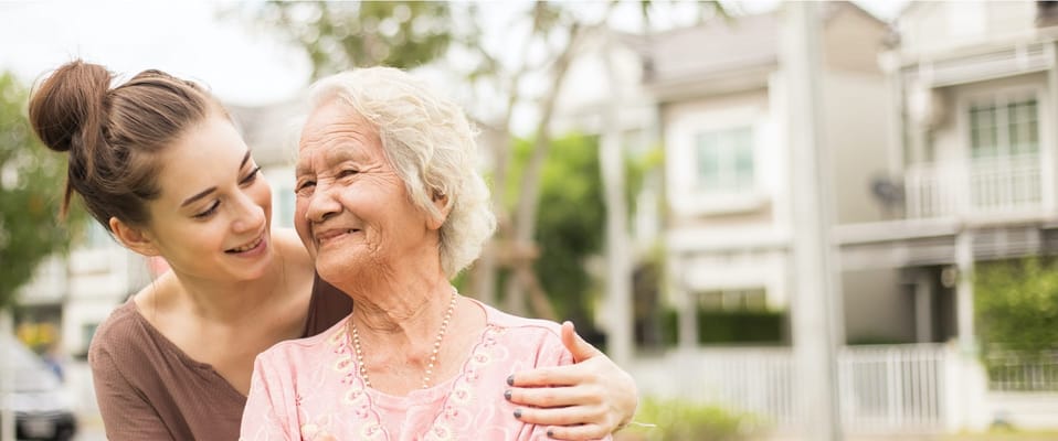 A caregiver smiling with an elderly resident outdoors