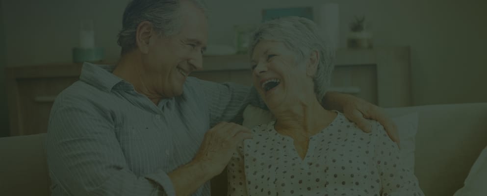 A senior couple laughing together on a couch