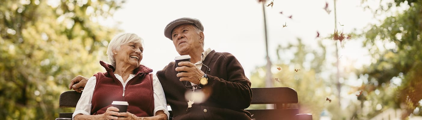 Couple enjoying coffee on a park bench