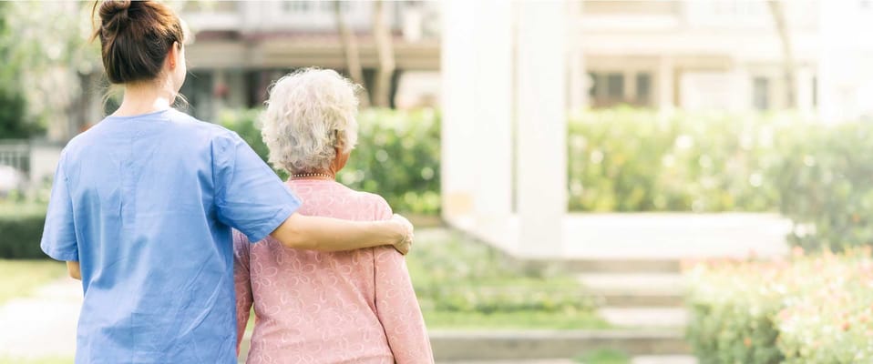 Staff assisting a resident in a garden area