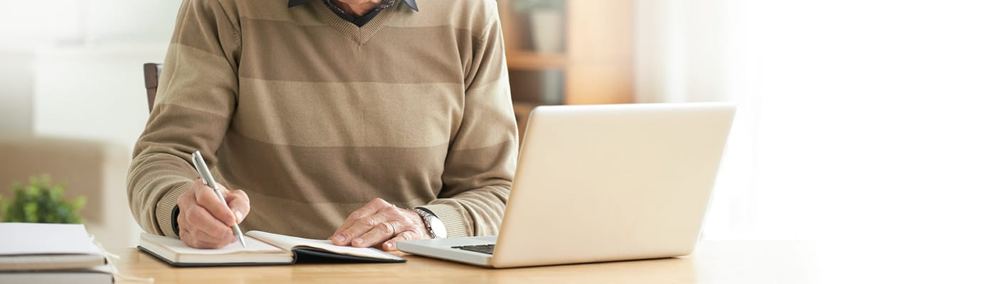 Senior resident writing in a notebook at a table