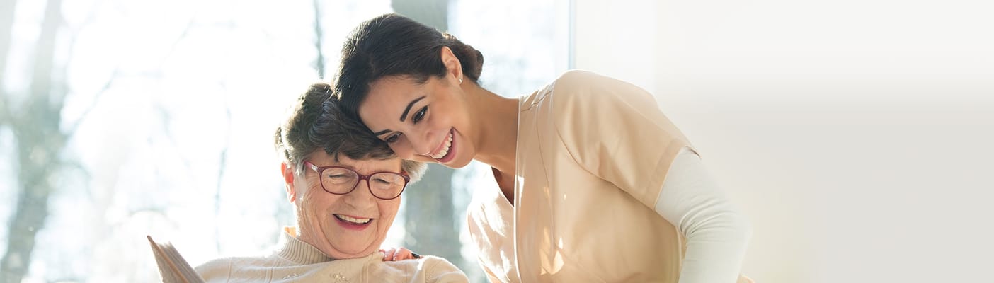 Staff member assisting a resident in a bright indoor space