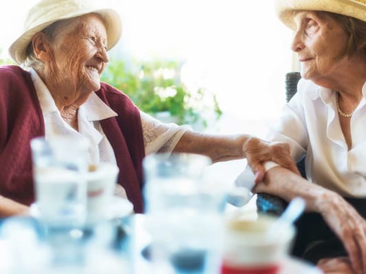 Two smiling elderly women enjoying a moment together
