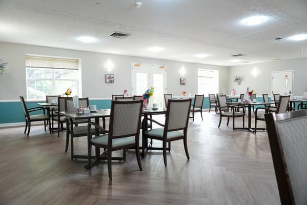 Dining area with tables and flowers, brightly lit