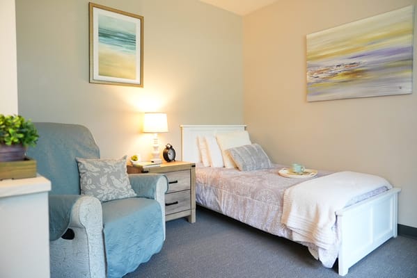 A cozy resident room with a bed and chair