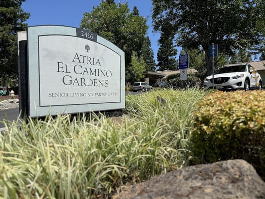 Sign for Atria El Camino Gardens in a landscaped area