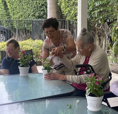 Senior residents planting flowers at a table outdoors