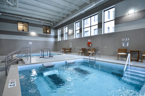 Indoor pool area with lounge chairs and safety signs