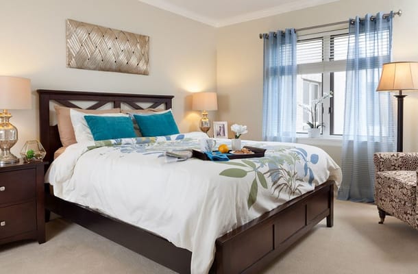 A cozy bedroom with a bed, blue cushions, and decorative elements.