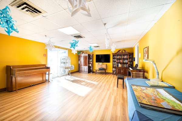 Bright common area with a piano and bookshelves