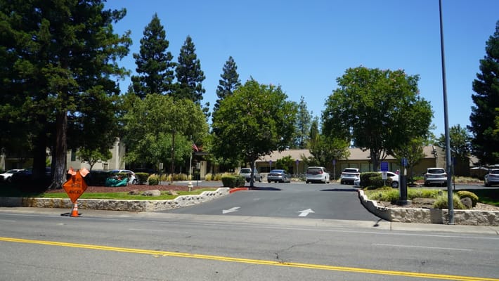 Entrance of a senior living facility with trees and cars
