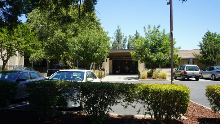 Front entrance of a senior living facility surrounded by trees