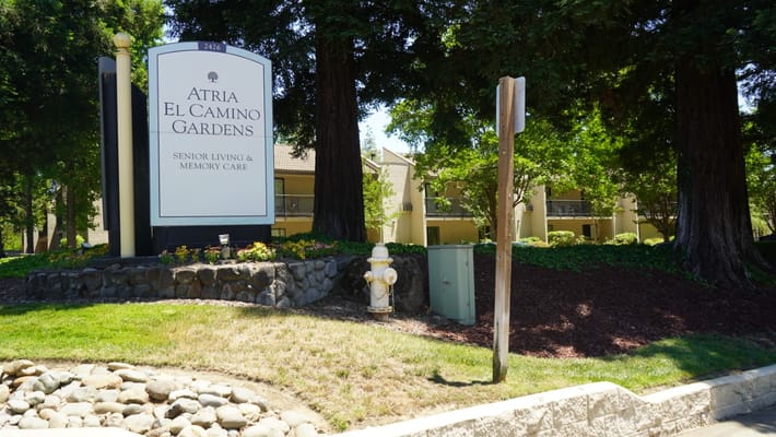 Sign for Atria El Camino Gardens surrounded by trees