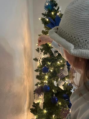 A resident decorating a Christmas tree indoors