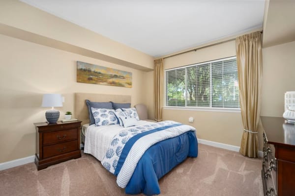 A well-furnished bedroom featuring a bed with blue and white bedding and a nightstand.