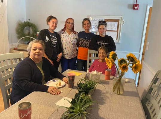 Residents and staff enjoying a meal together at the dining table