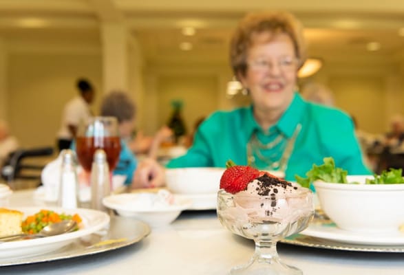 Resident enjoying a meal with dessert at the dining room