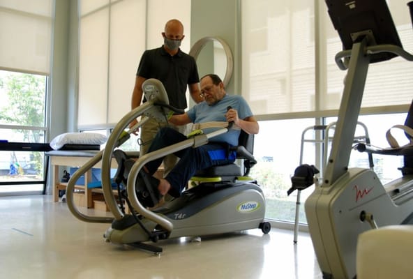 Staff assisting a resident with rehabilitation equipment