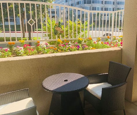 Outdoor seating area with colorful flowers and a decorative sign