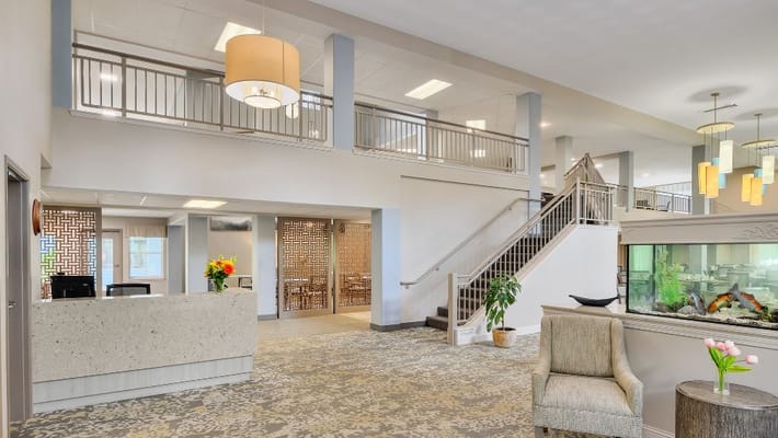Brightly lit lobby area with reception desk and staircase