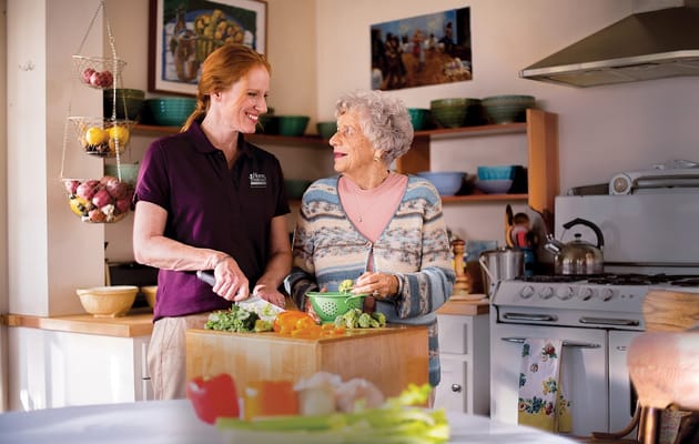 Staff helping a resident prepare food in a kitchen