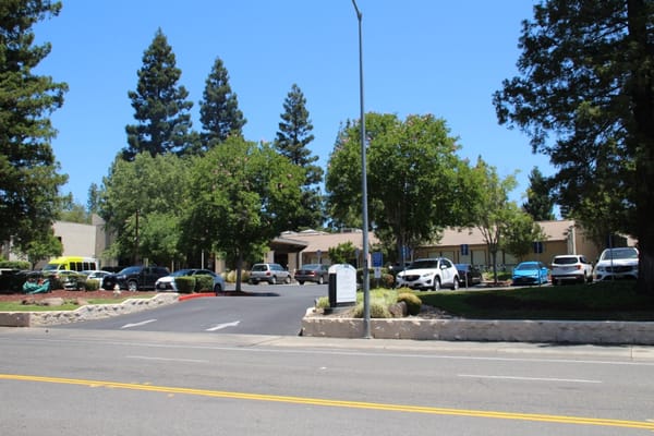 Exterior view of a senior living facility with trees and parking