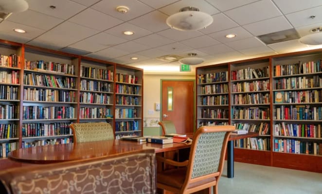 Cozy library featuring shelves filled with books and a study table