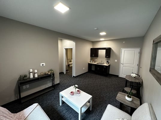 A modern living room with a small kitchenette and comfortable seating.