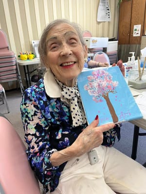 Resident painting a flowering tree in an activity room