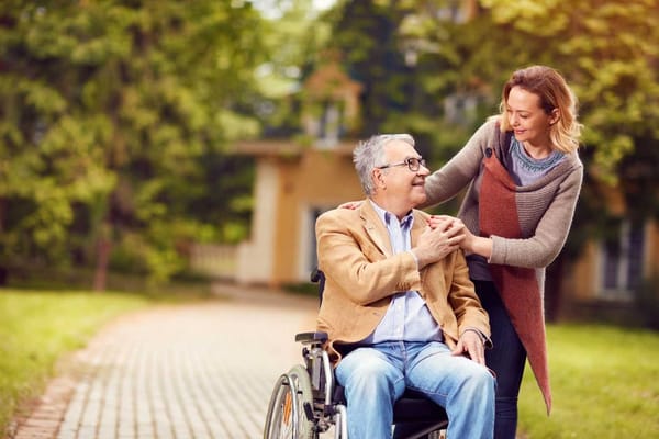 A woman assisting a man in a wheelchair outdoors
