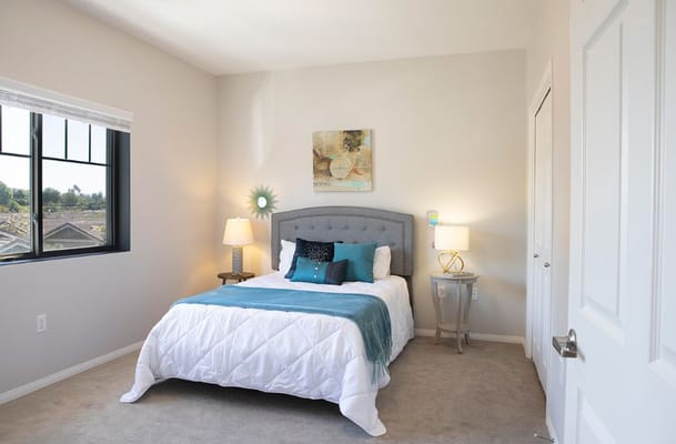 A well-decorated bedroom with a bed, nightstand, and window.