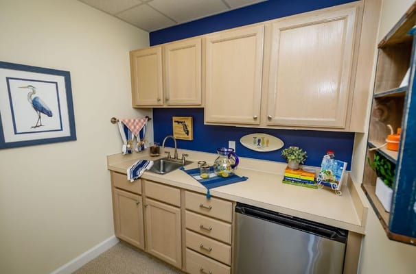 Compact kitchenette with light wood cabinets and blue accent wall