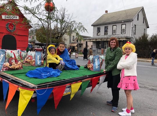 Participants in parade float with Snoopy decoration and colorful blankets.