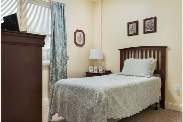 A well-decorated bedroom with a single bed, bedside table, and window