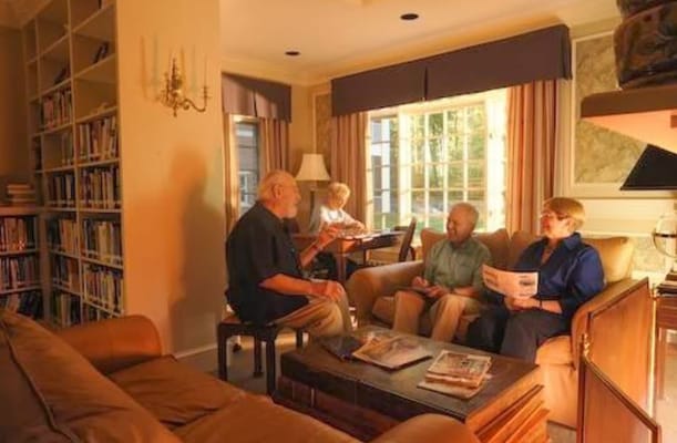 Four senior residents in a cozy living room discussing together