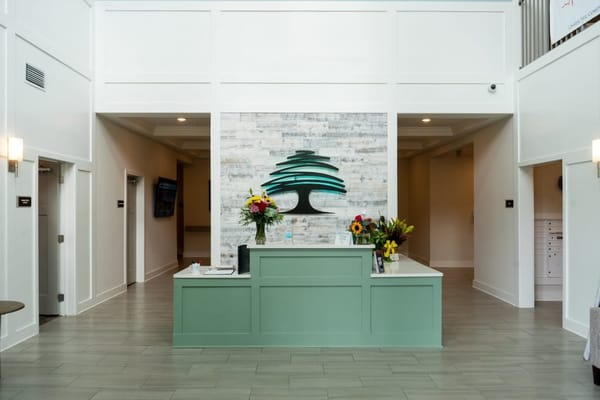 Reception desk with floral arrangements and tree artwork