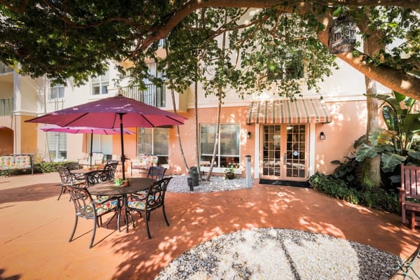 Patio area with seating and umbrellas at The Carlisle Assisted Living.