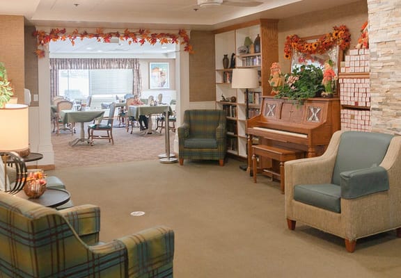 Cozy living room with seating and a piano in The Chateau at Sharmar Village