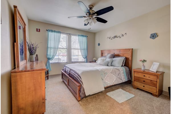 A well-decorated bedroom featuring a wooden bed frame, dresser, and blue curtains.