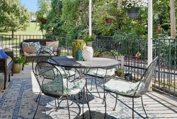 Outdoor patio with table and chairs surrounded by greenery