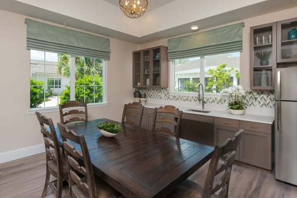 Wooden dining table and kitchen area with windows