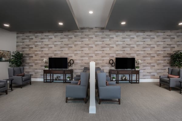 Lounge seating area with gray chairs and a wooden TV stand