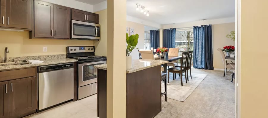 Modern kitchen leading into a dining area with a table and chairs.