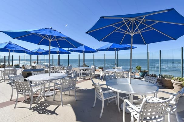 Patio area with blue umbrellas overlooking the ocean