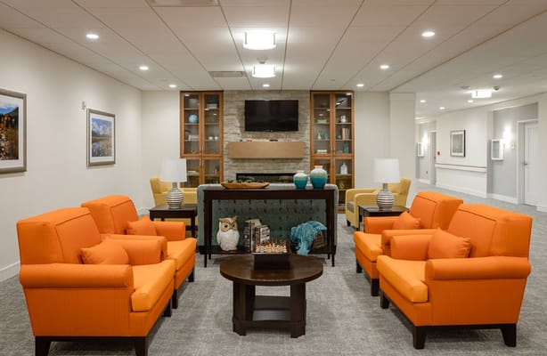 Lounge area featuring orange chairs and a stone fireplace