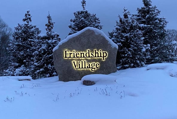 Entrance stone sign for Friendship Village in snow