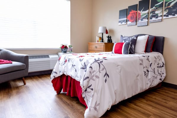 Well-decorated bedroom with a bed, chair, and natural light