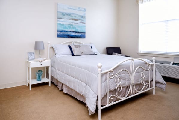 Neatly arranged bedroom with a bed, nightstand, and artwork